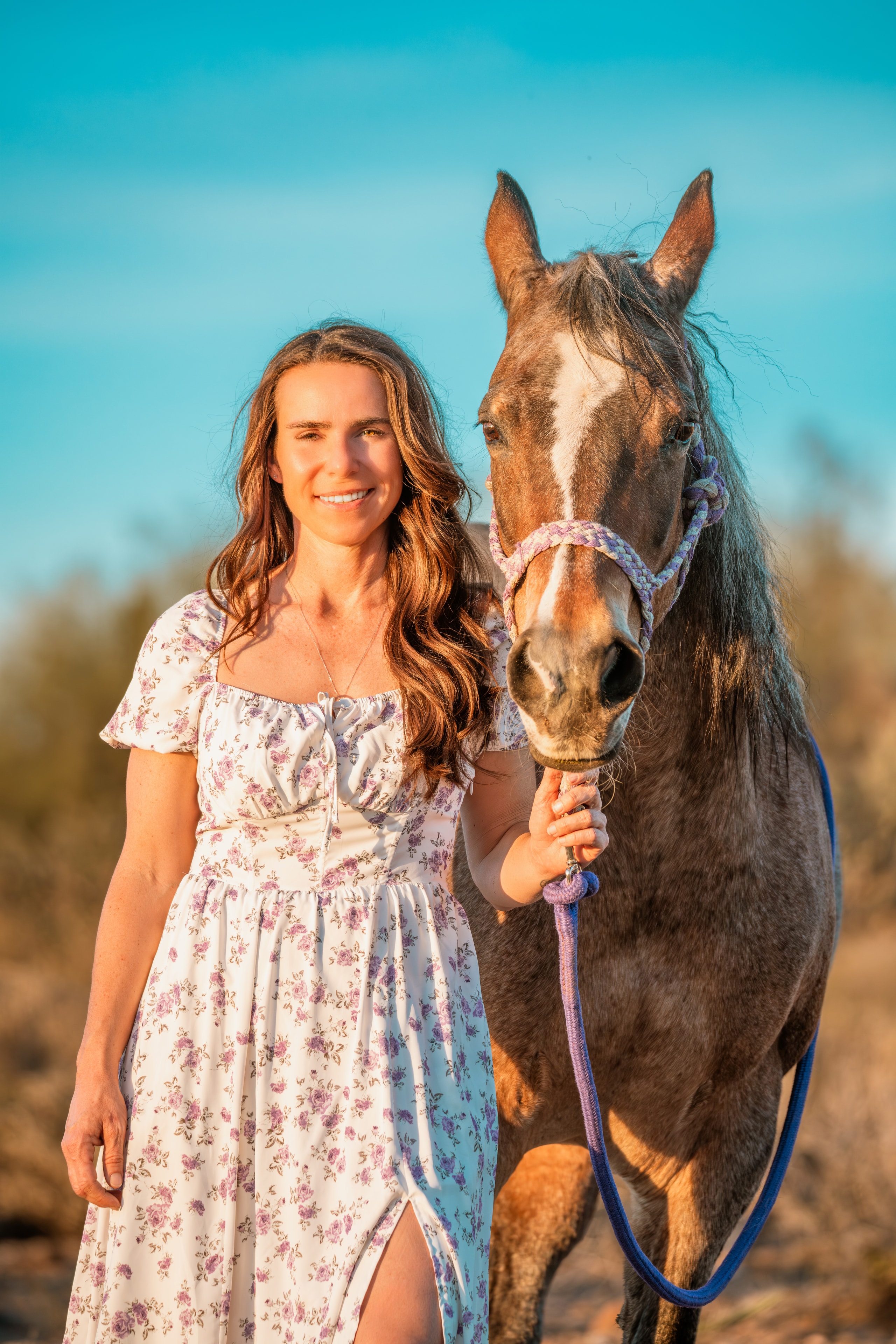 Woman standing with her horse under a bright turquoise sky