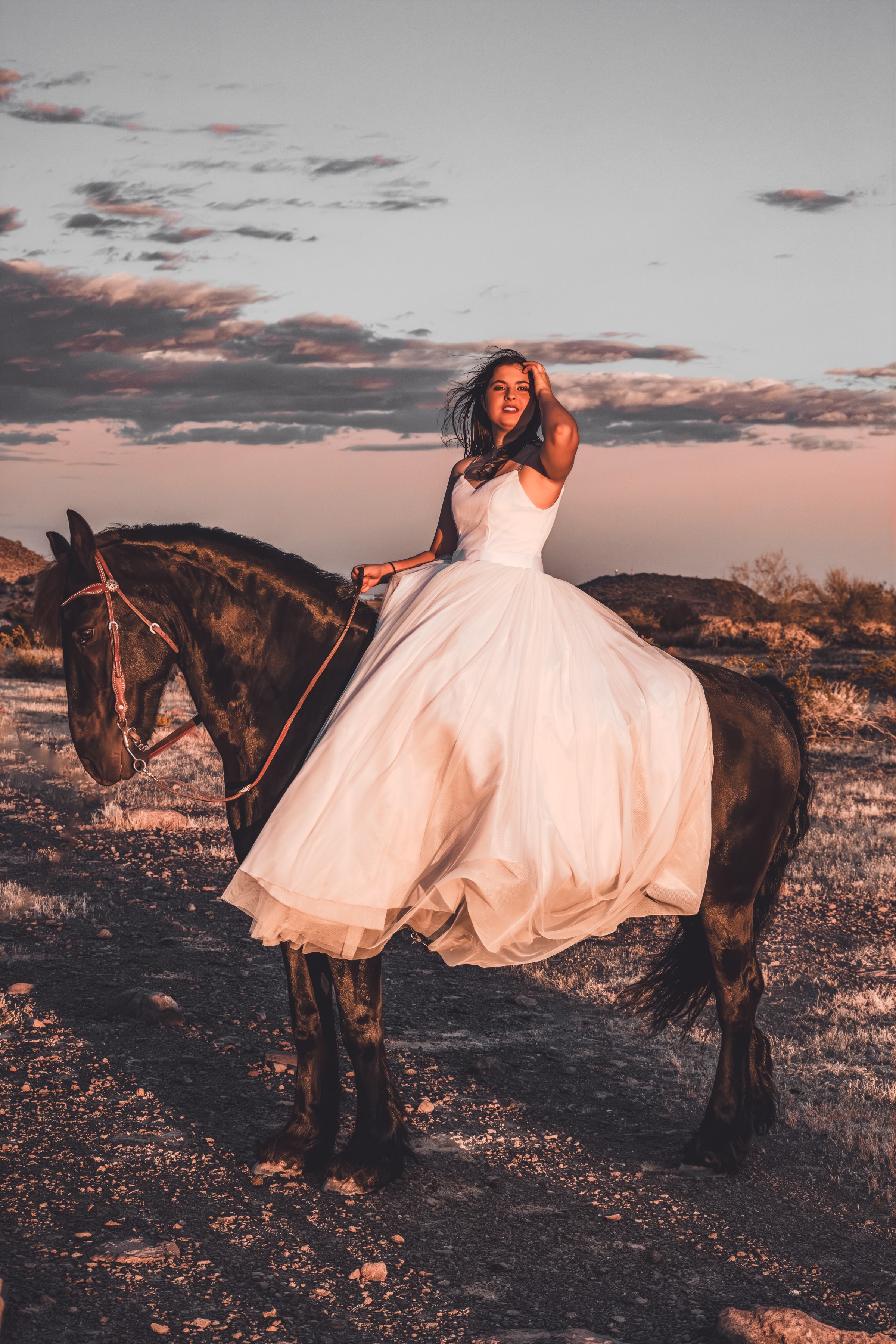 Rider in a flowing white dress on horseback at dusk